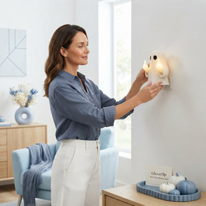 A woman calmly setting up a GhostFlip decoration in a bright, modern living room with blue accent decor.